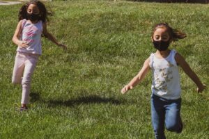 Kids play outside with masks on.