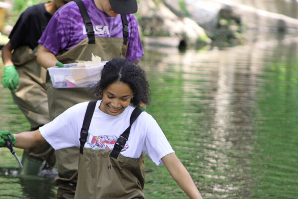 Texas high school students walking through creek with specimens.